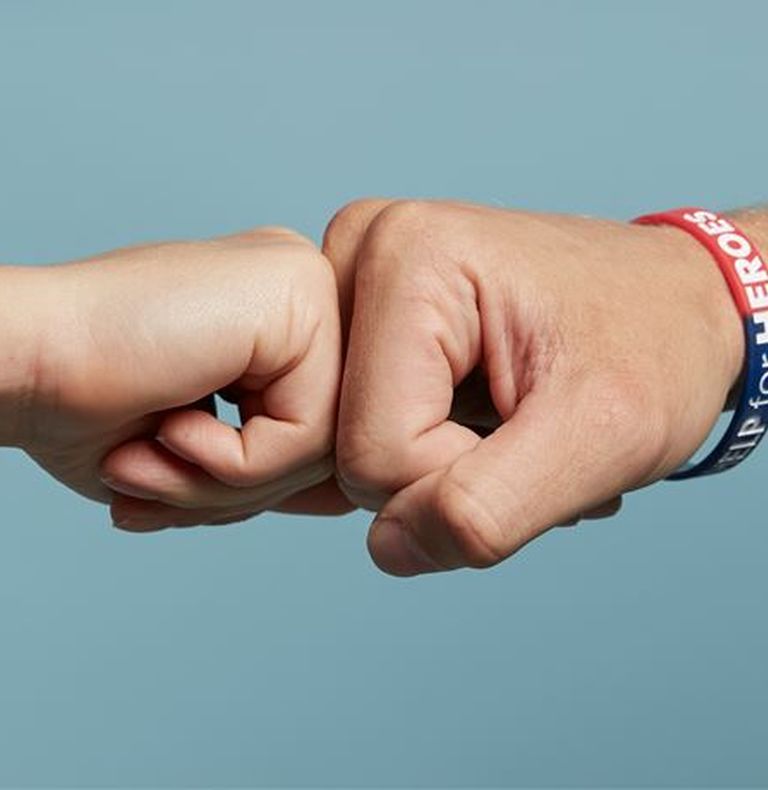 Two people, both wearing Help for Heroes hoodies, standing next to each other with their arms around each other looking at the camera